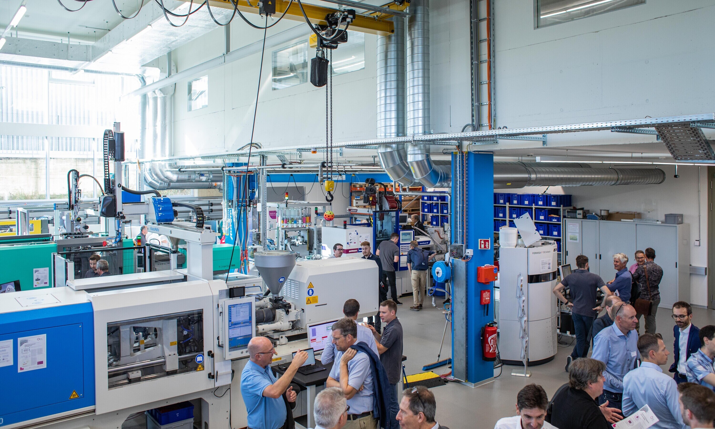 iwk_website_veranstaltungen_startseite Personen stehen in Maschinenhalle im Techpark vom IWK anlässlich des Rapperswiler Kunststoff-Forums