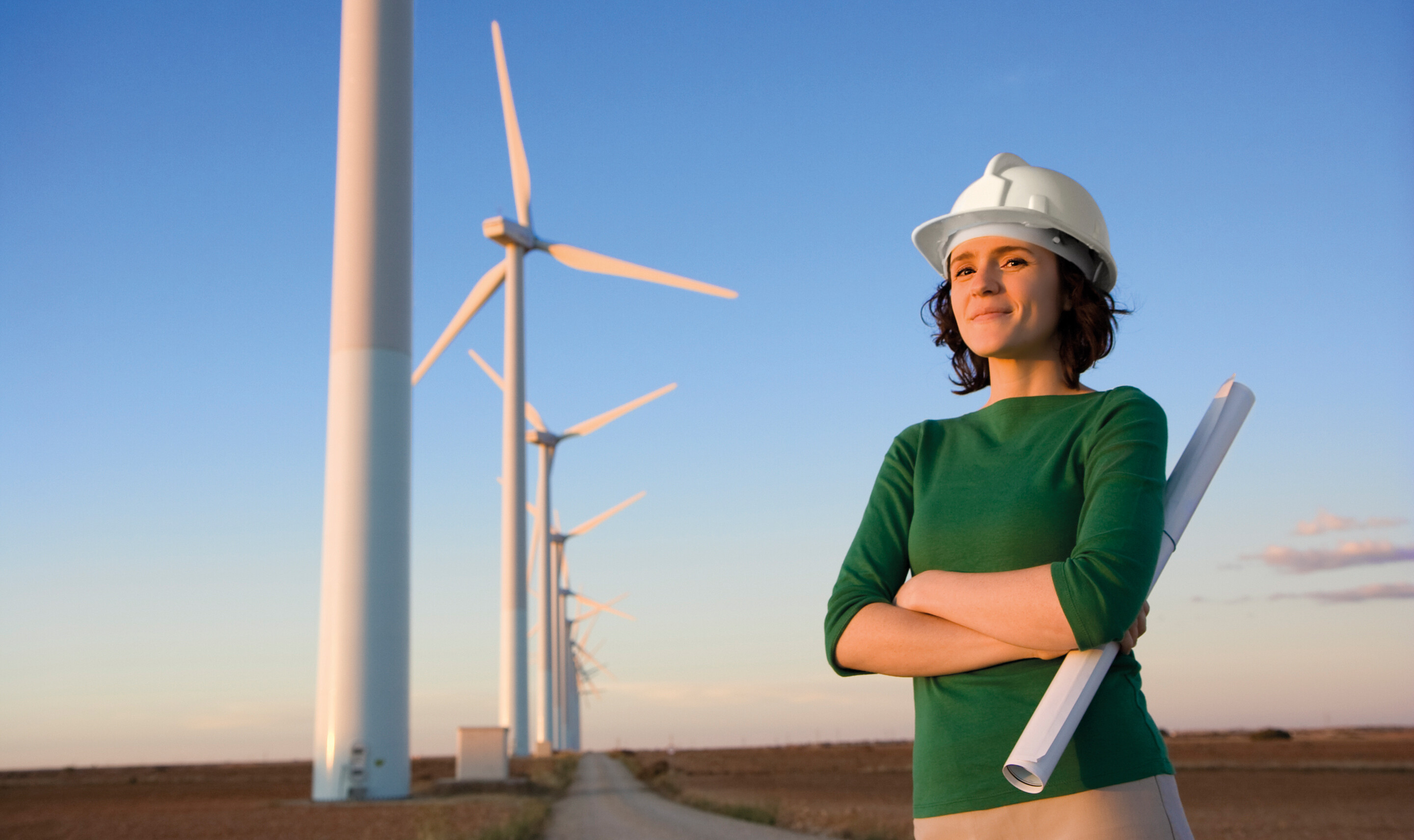 Frau mit Helm vor Windenergie-Anlage
