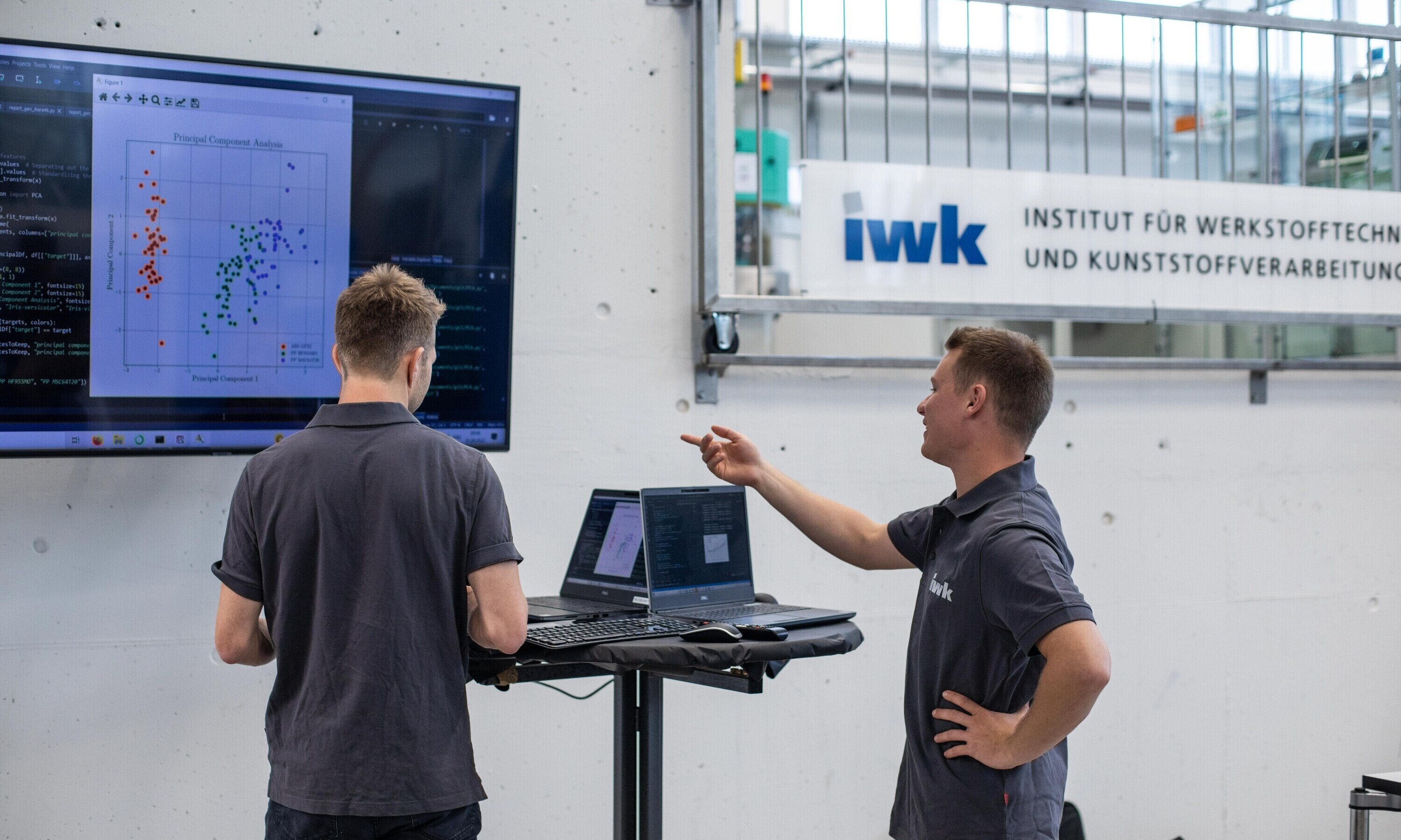 iwk_website_zusammenarbeit_startseite Mitarbeitende im Techpark am IWK stehen in Maschinenhalle und diskutieren über ein Projekt