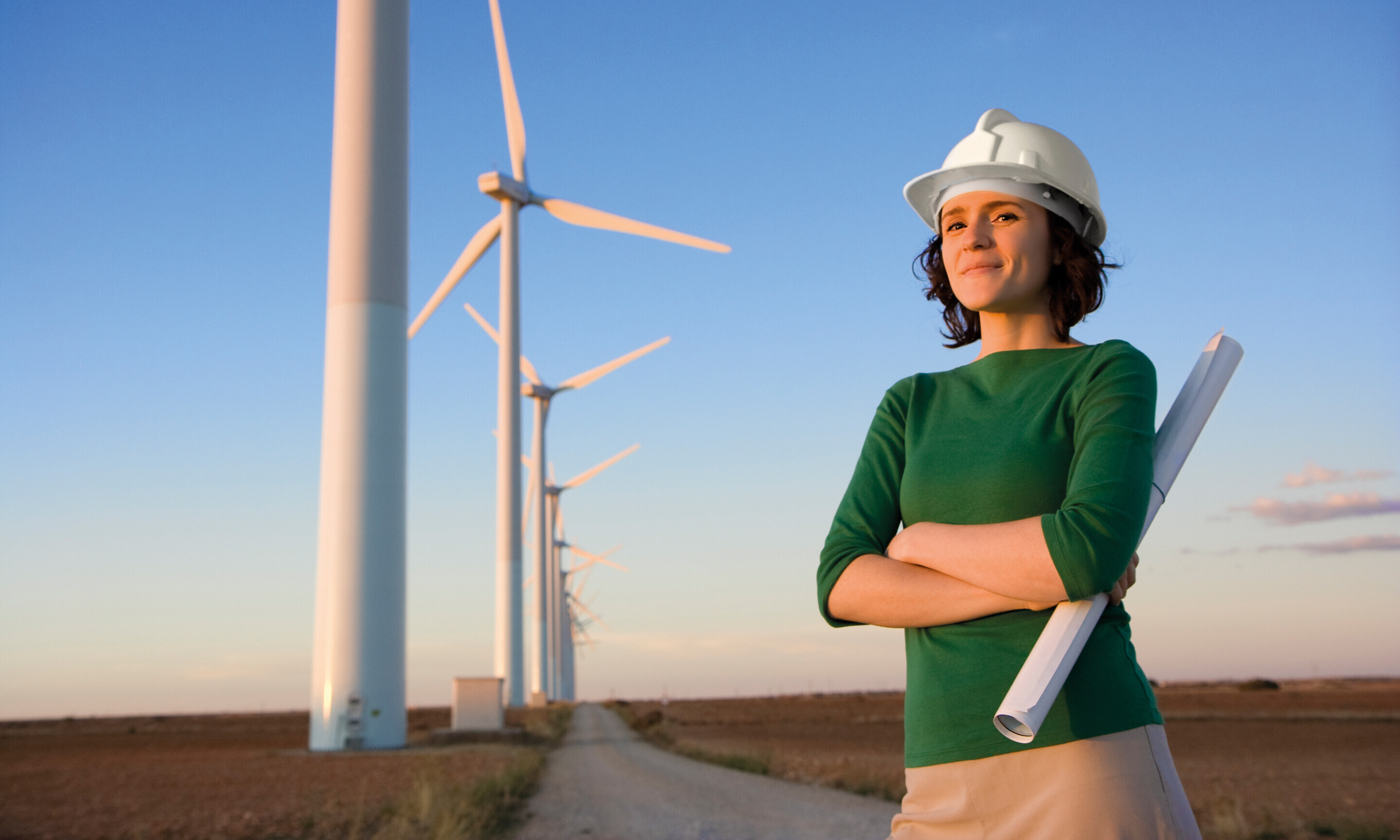 Weiterbildung: Wie Windenergie nutzen? Frau mit Helm vor Windenergie-Anlage