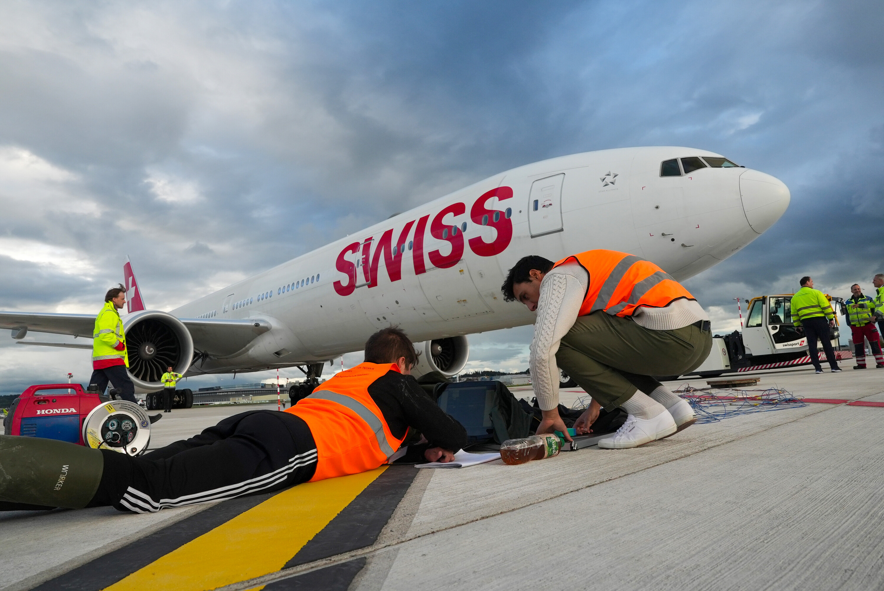 Eine Boeing 777 der SWISS steht auf dem Flugfeld. Zwei Mitarbeiter der OST arbeiten an den Messgeräten.