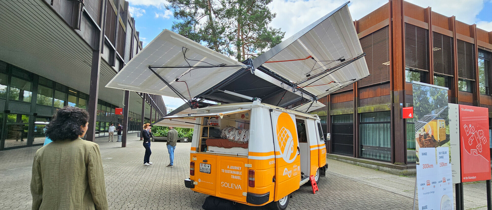 VW-Bus mit Solarpanels auf Dach vor einem Gebäude des Campus OST Rapperswil