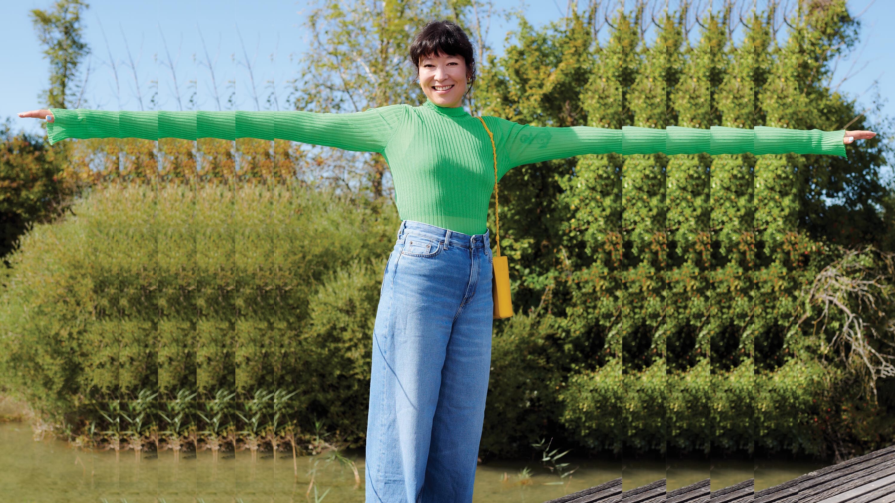 Eine Frau streckt die Arme aus. Im Hintergrund Natur. 