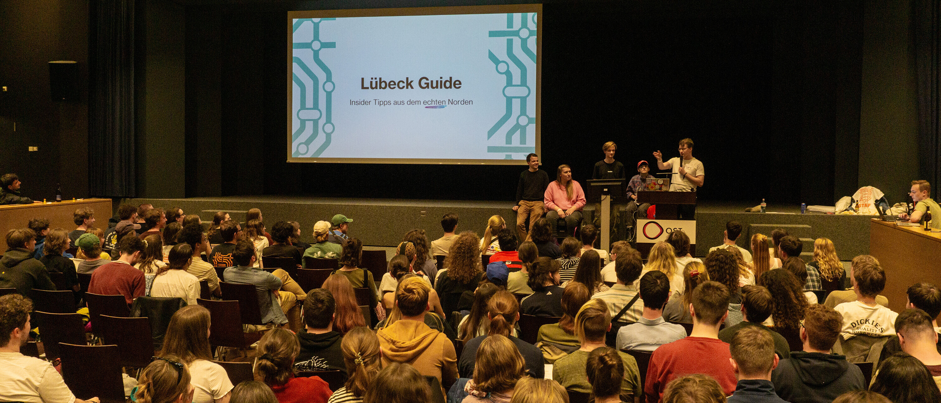 Powerpointkaraoke: Auch Humor und Städterivalität darf nicht fehlen: Im Rahmen der Stadtaufgabe musste jeder teilnehmende Standort eine Präsentation zur Unistadt vorbereiten. Ein anderer Standort stellte diese dann dem Saal vor (Foto: Matteo Ruckstuhl)