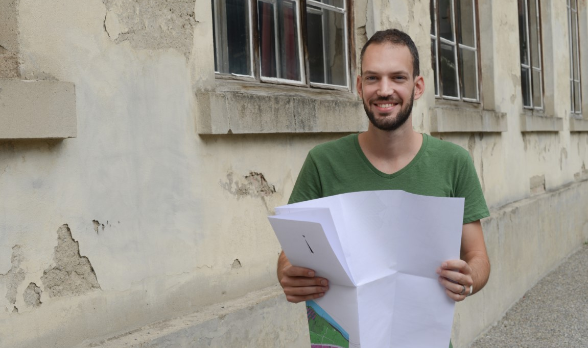 Junger Mann mit aufgefaltetem Stadtplan