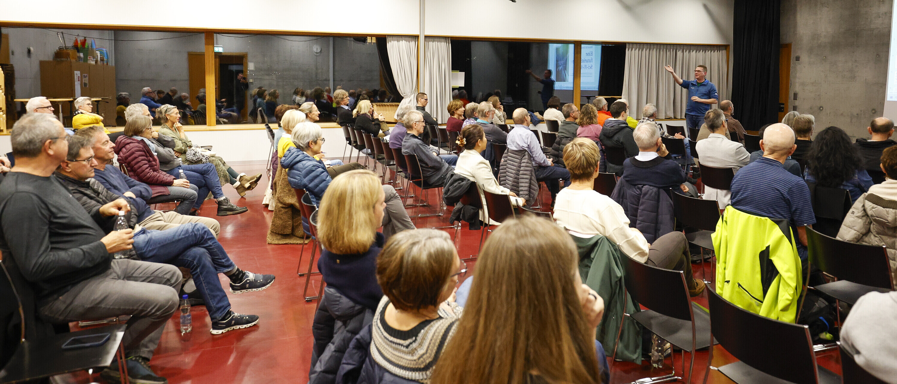 Ost Seminar KI und Kreativität: " Booster oder Killer? Zahlreiche Personen sitzen in einem Seminarraum und verfolgen eine Präsentation. Vorne im Raum steht der Referent.