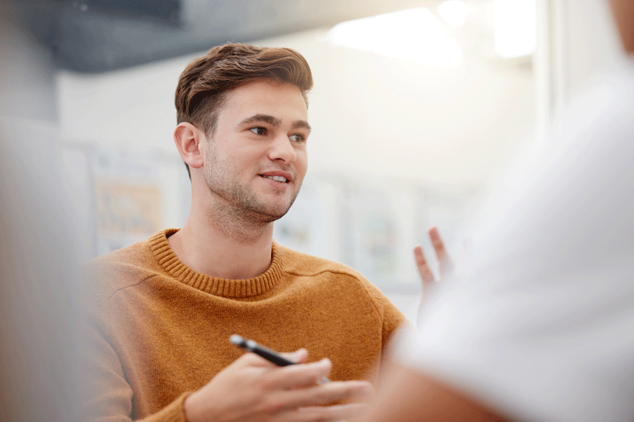 Ein junger Mann des Studiums Ergotherapie mit Kugelschreiber in der Hand