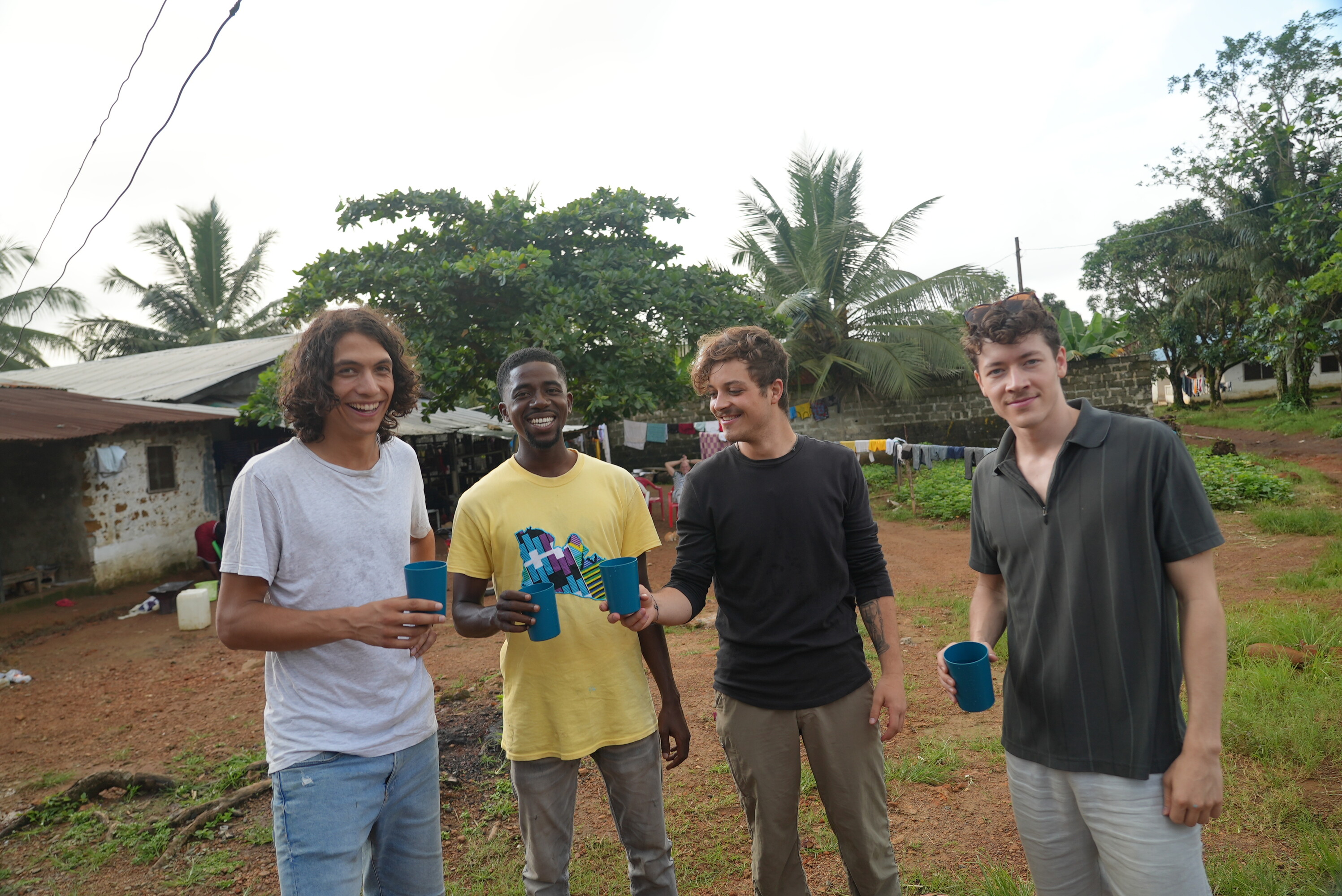 Studierende aus der Schweiz und Liberia stossen mit einem Glas Wasser auf den solarbetriebenen Wasserkiosk in Monrovia an.