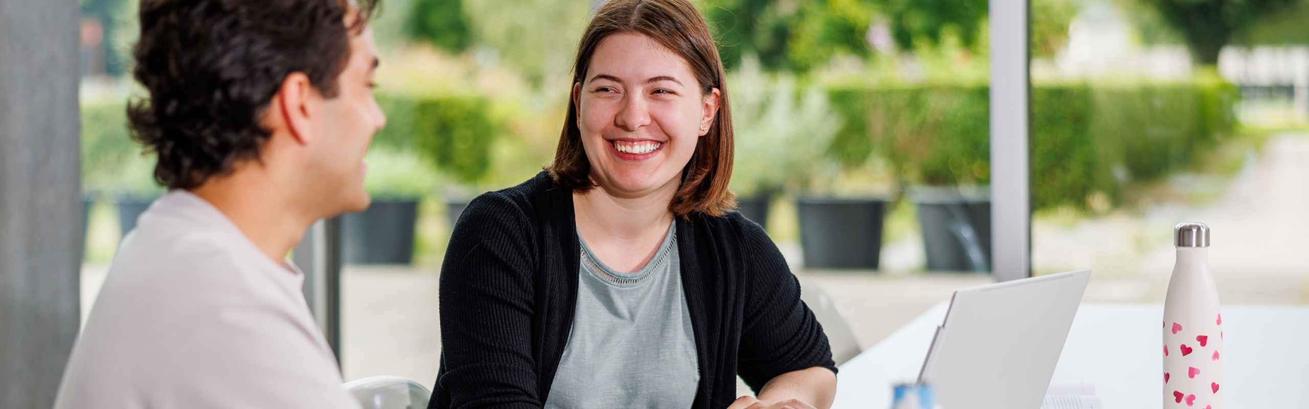 Zwei Studierende des Bachelor Wirtschaftsinformatik im Campusgebäude Zwei Studierende des Bachelor Wirtschaftsinformatik sitzen am Laptop, besprechen etwas