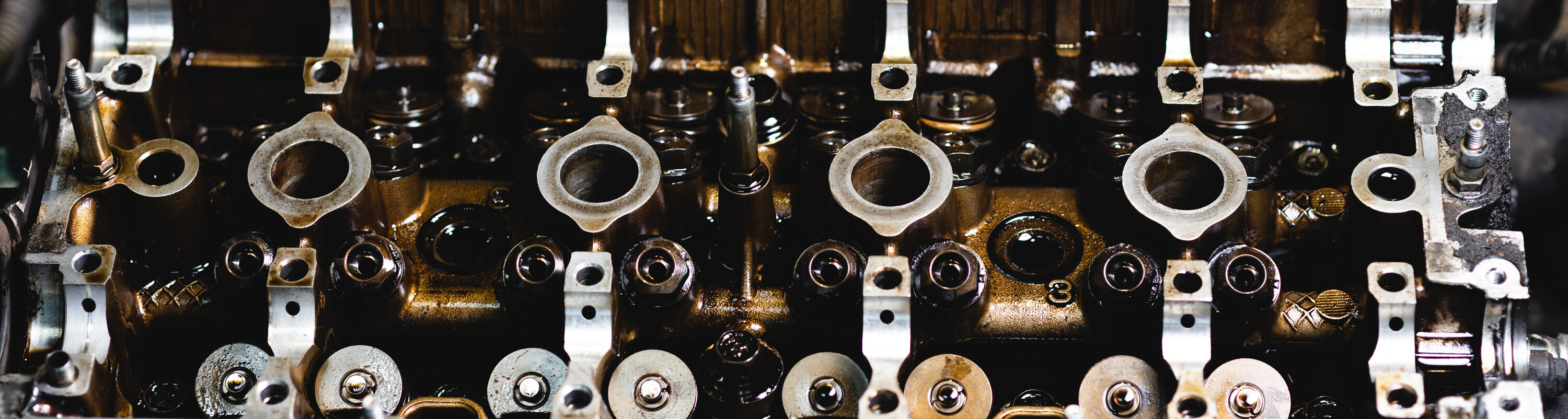 Disassembled car engine in oil. Cylinder head of an automobile engine. Inside the car being repaired. Sixteen valves. Car maintenance